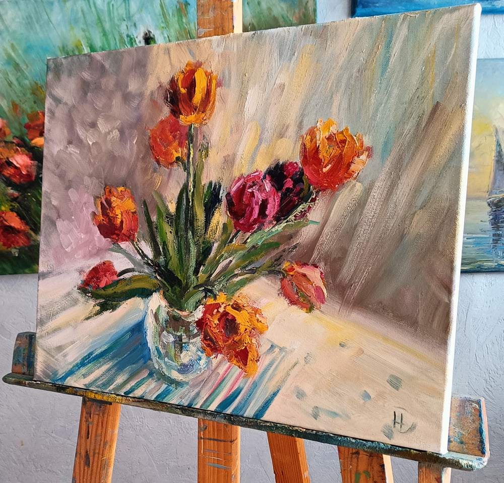 Картина с тюльпанами в вазе на мольберте.